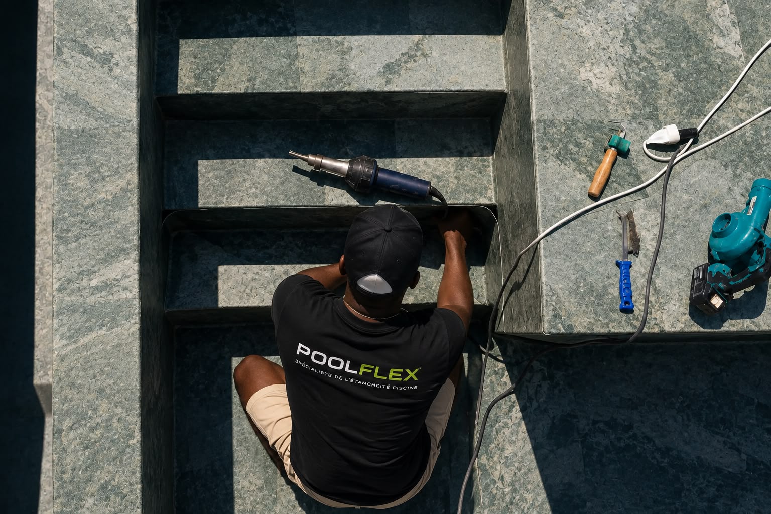 Technicien Poolflex soudant à chaud une membrane armée sur les marches d’un bassin